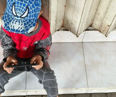 Chlapeček v oblečení Spider-Mana sedí na zemi.