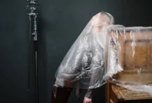 Žena je zahalená igelitem u klavíru.