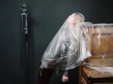 Žena je zahalená igelitem u klavíru.