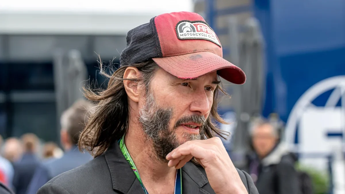 Keanu Reeves si podpírá hlavu.