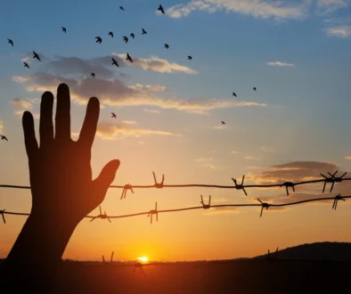 Ruka mává před ostnatým drátem.