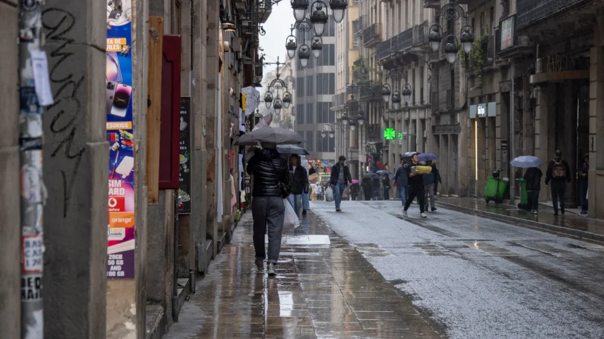Lidé se v dešti prochází Barcelonou.