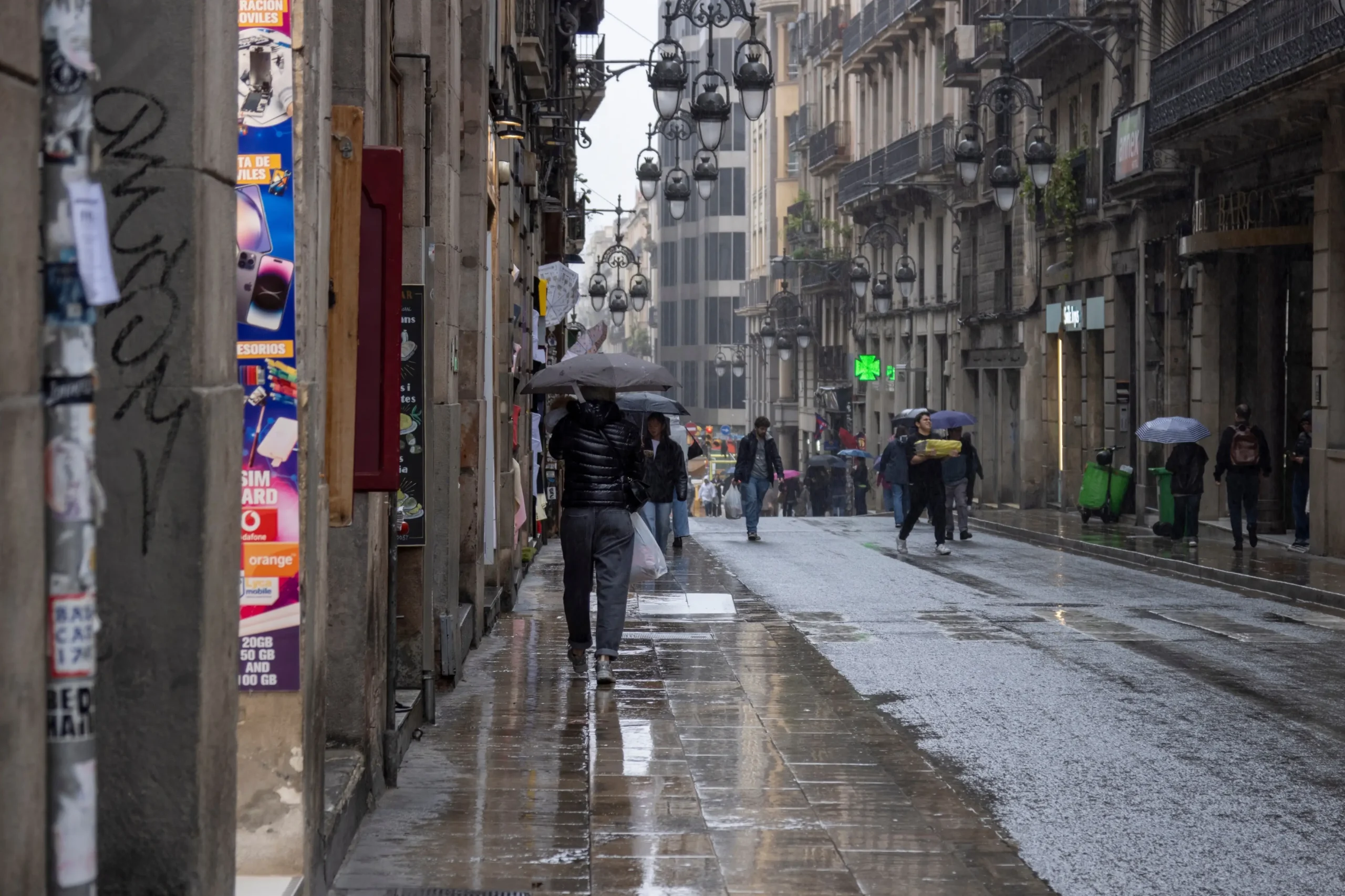 Lidé se v dešti prochází Barcelonou.