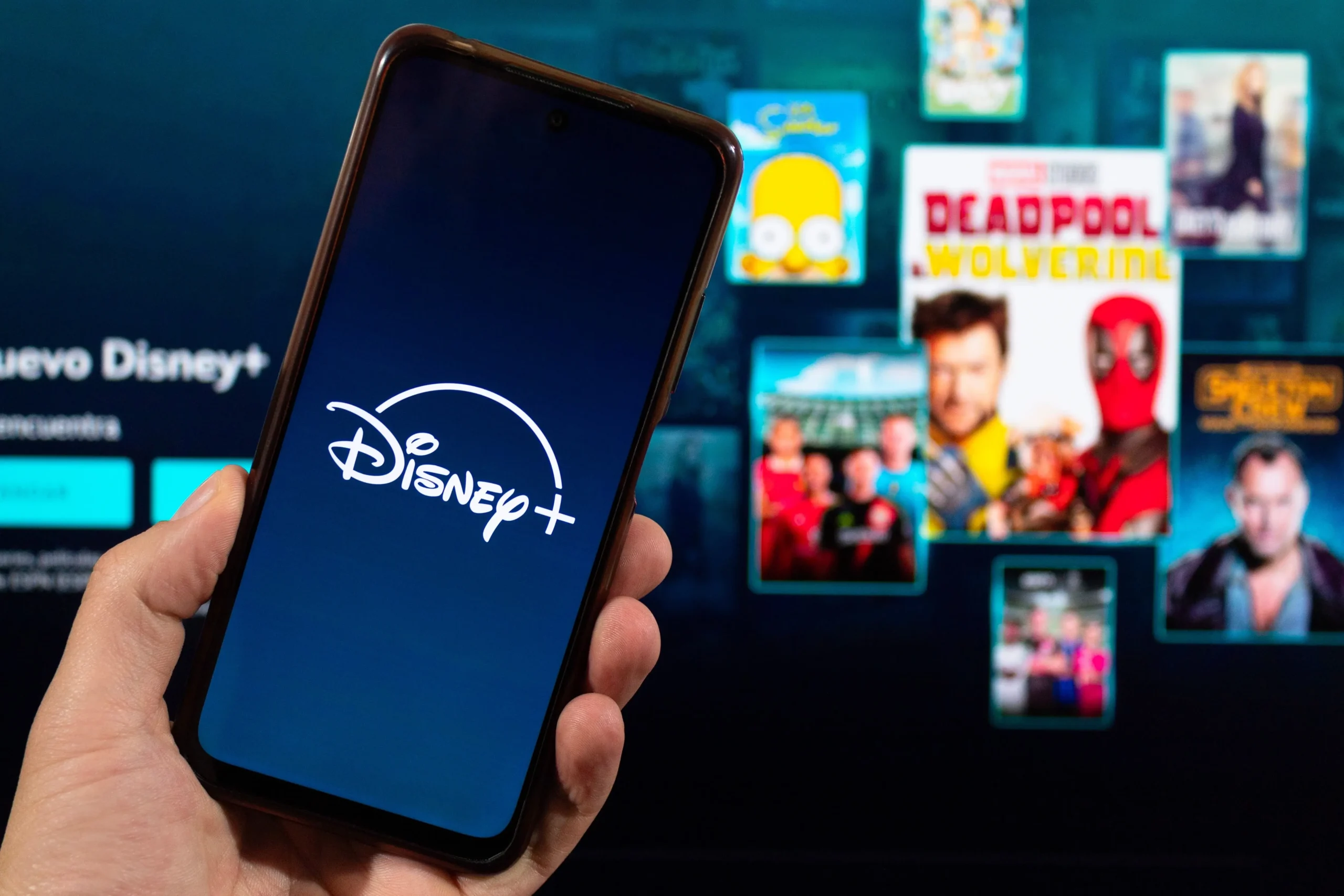 Muž drží telefon s aplikací Disney+