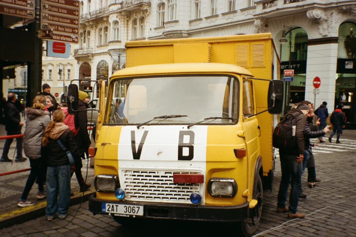 Lidé stojí u zaparkovaného auta VB.