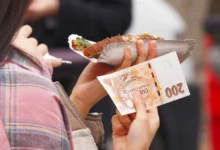 Žena v jedné ruce drží jídlo a v druhé bankovku.