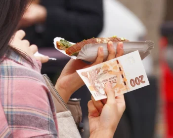 Žena v jedné ruce drží jídlo a v druhé bankovku.