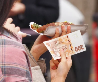 Žena v jedné ruce drží jídlo a v druhé bankovku.