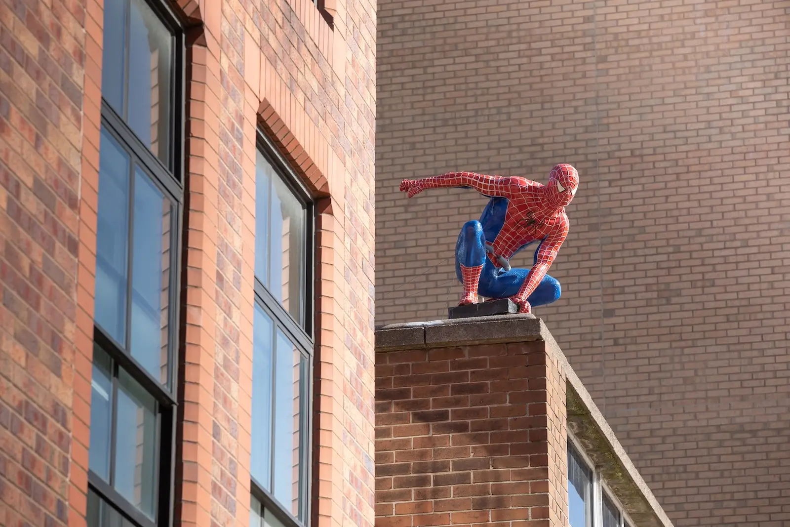 Spider-Man dřepí na okraji budovy.