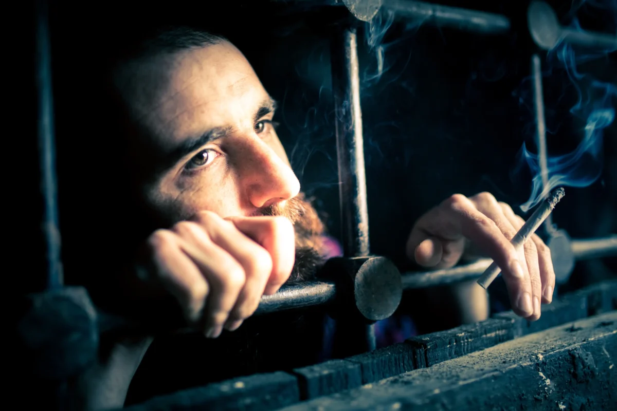 Muž skrze mříže kouří. 