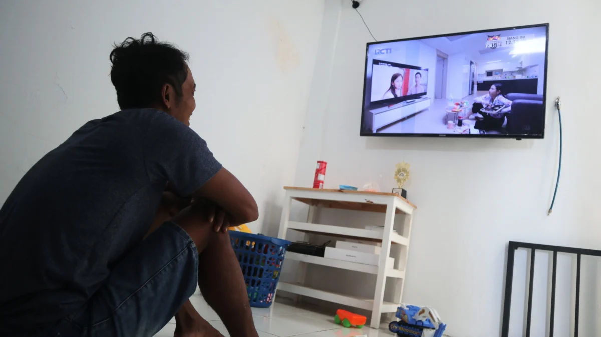 Muž sedí před televizí.