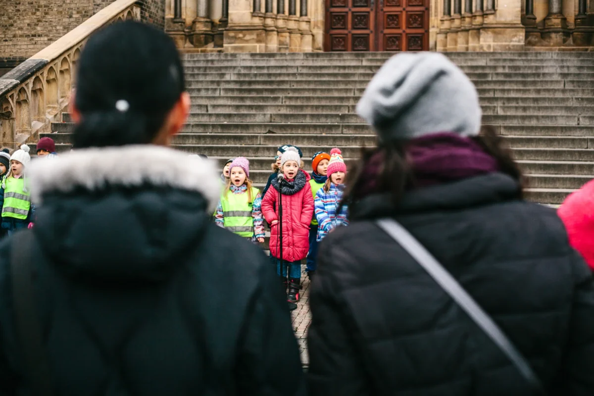 Děti zpívají ve sboru a rodiče se na ně koukají. 
