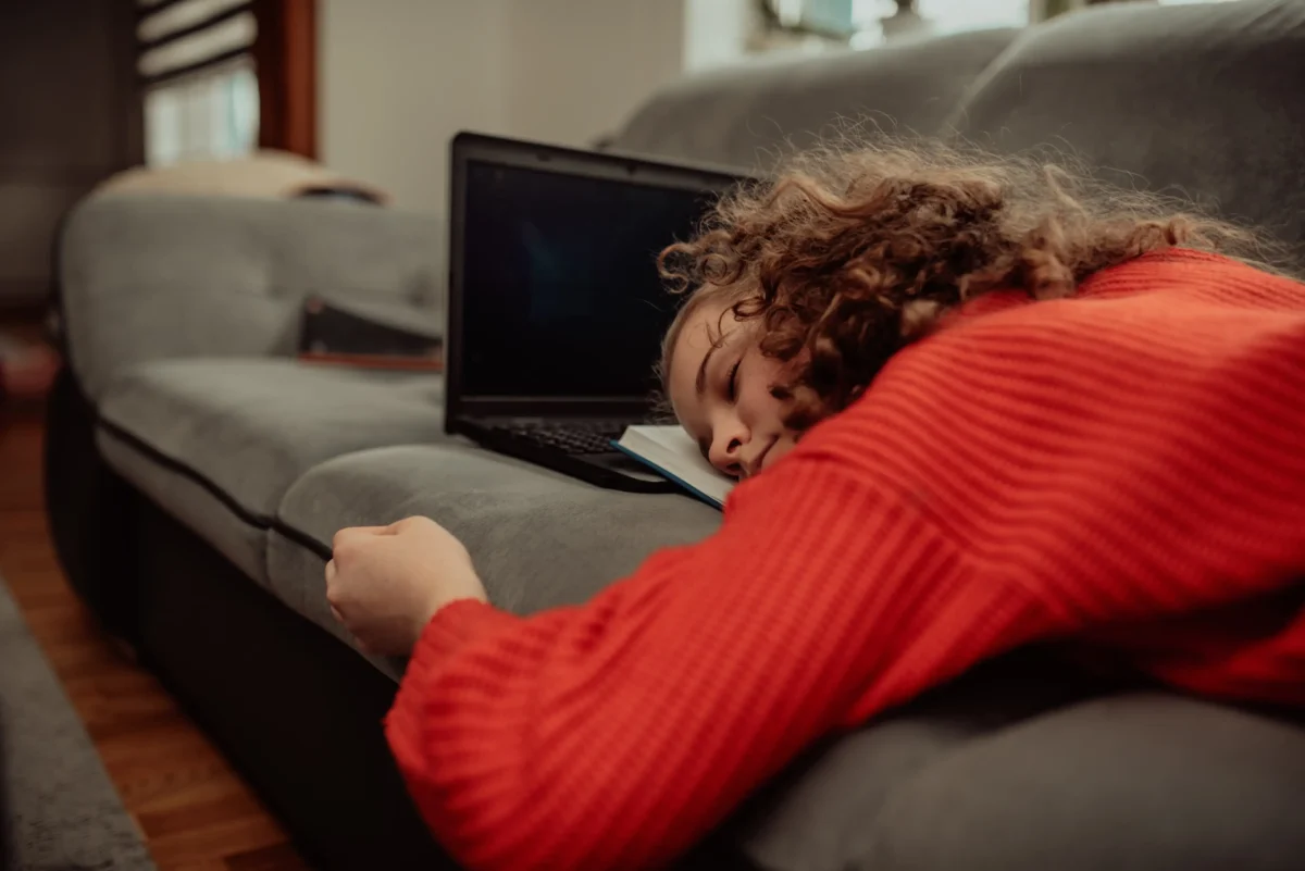 Holčička spí na notebooku.