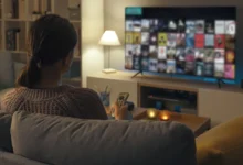 Žena sedí na pohovce před TV.