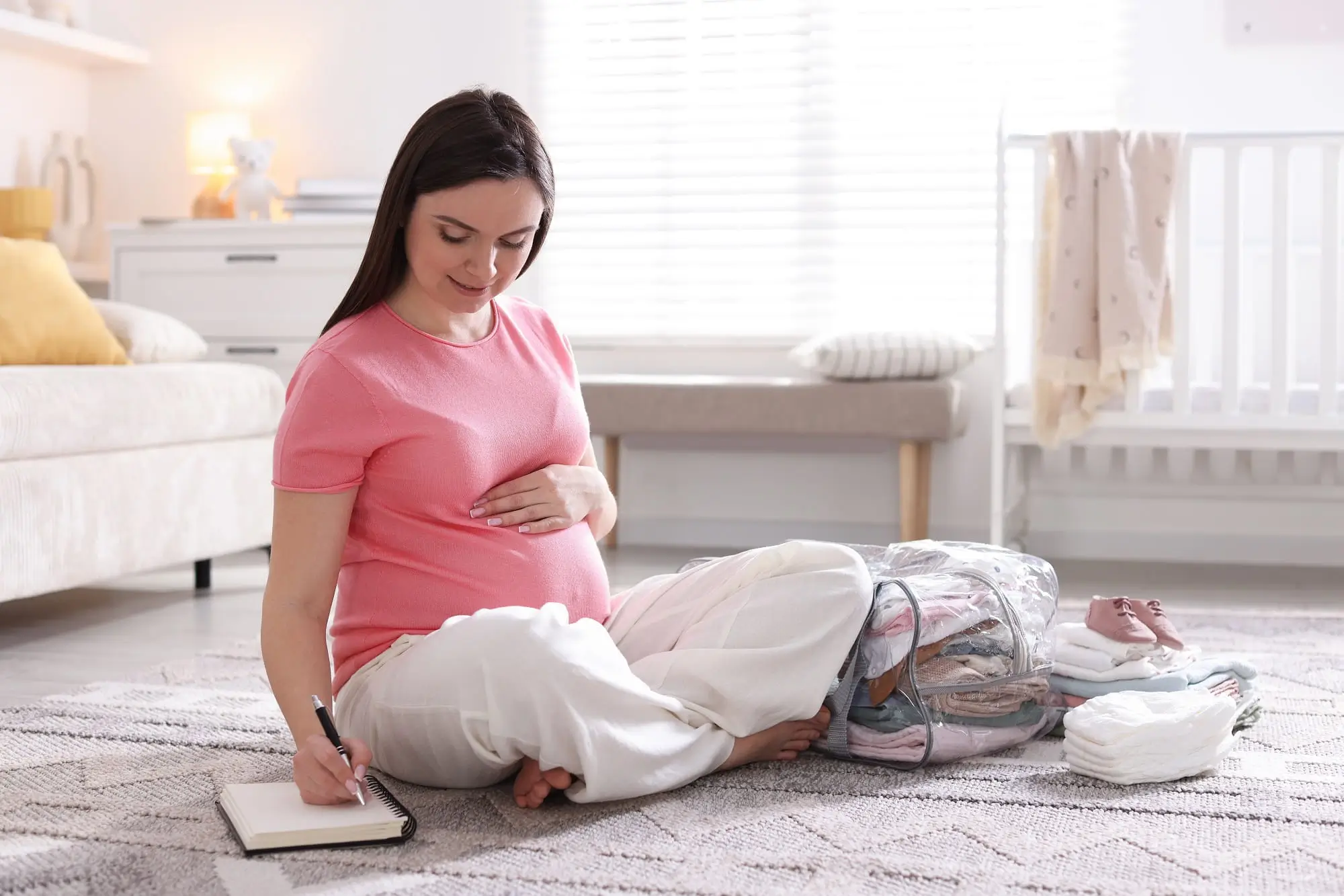 Těhotná žena sedí na zemi.