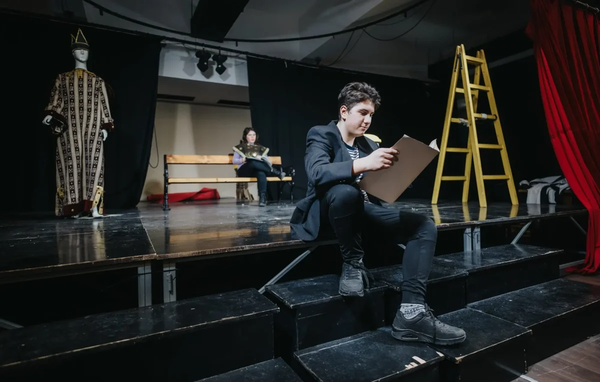 Chlapec sedí v divadle na zemi. 