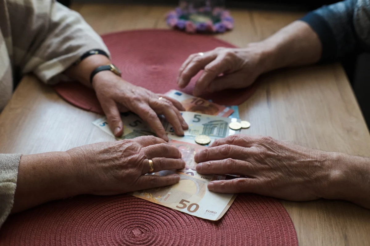 Staří lidé na stole drží peníze.