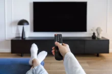 Muž sedí před tv s ovladačem v ruce.