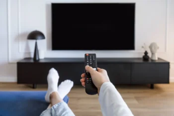 Muž sedí před tv s ovladačem v ruce.