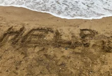 Nápis HELP na pláži.