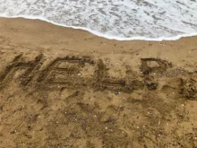 Nápis HELP na pláži.