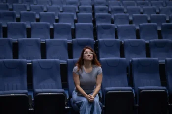 Žena sedí sama v kině.