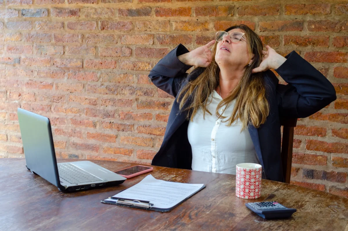 Žena sedí a chytá se za krk.