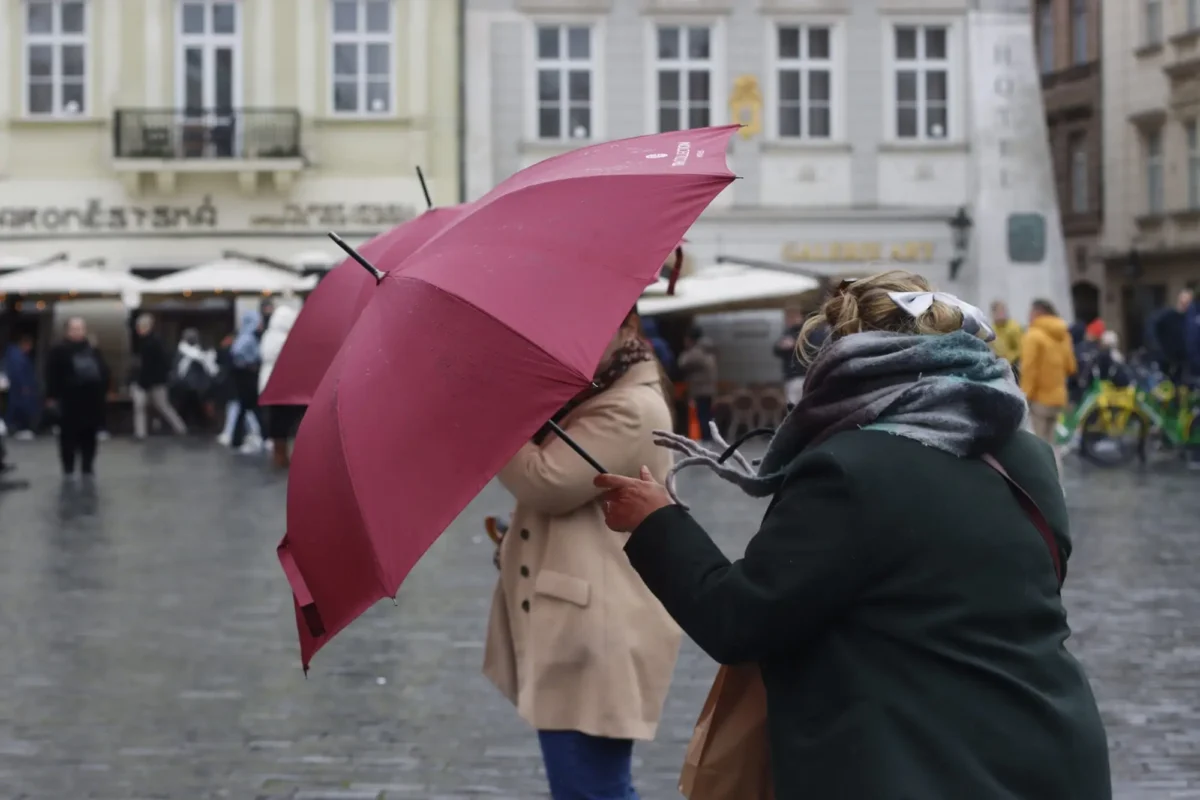 Ženy si přidržují deštníky. 