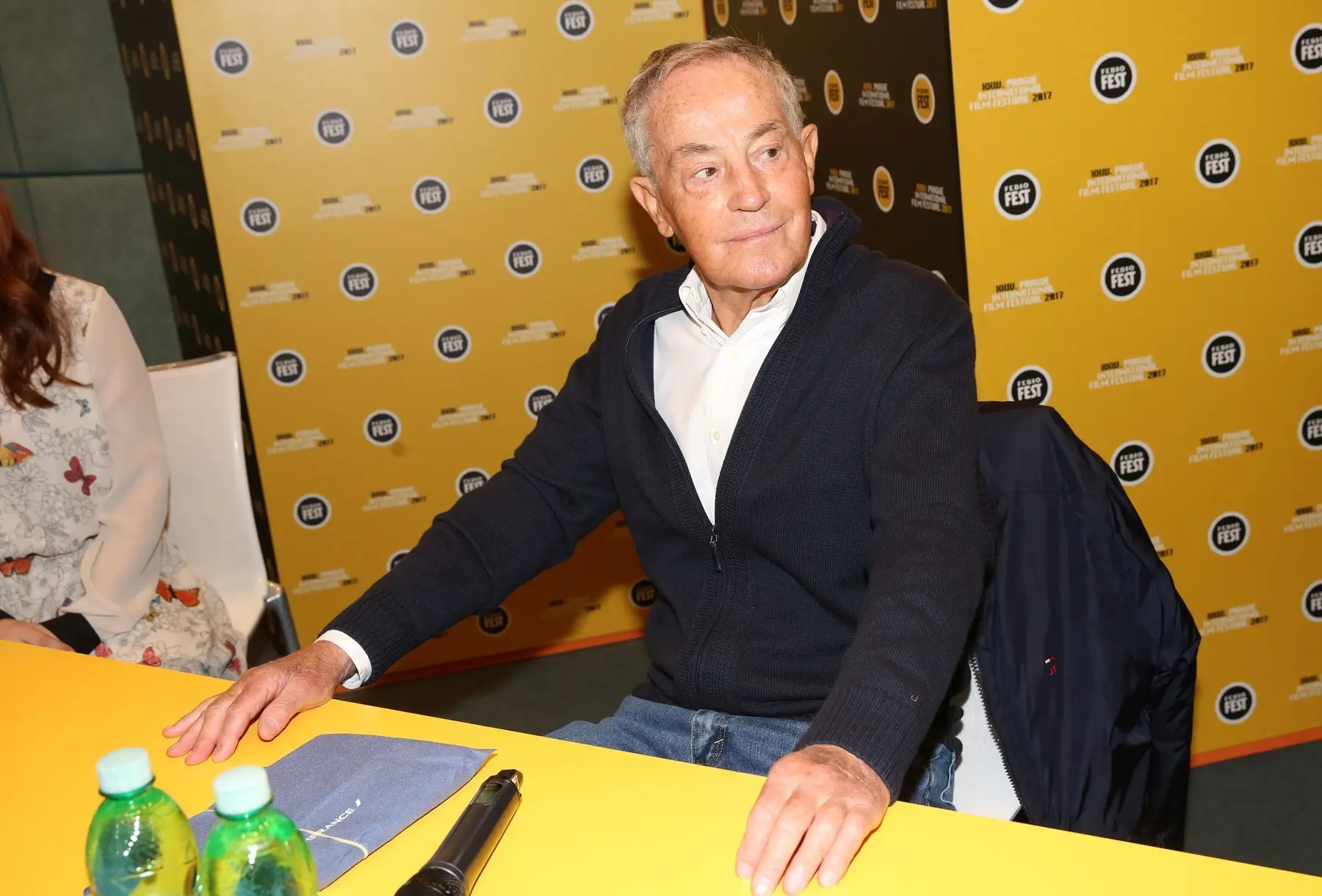 Jan Tříska sedí na židli. 