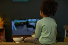 Dítě sedí před televizí.