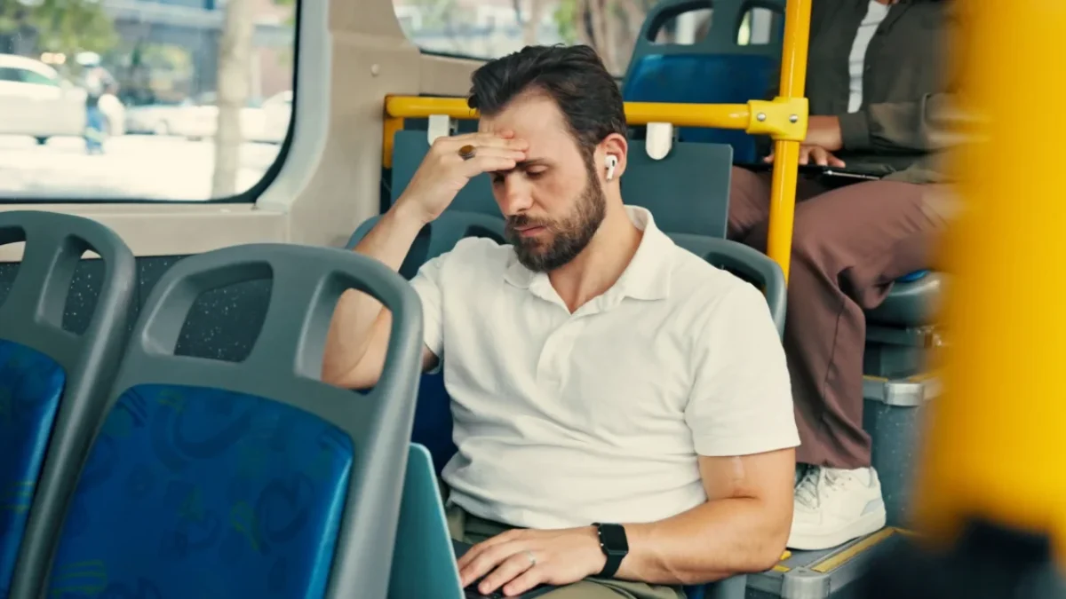 Muž jede v autobusu a drží se za hlavu