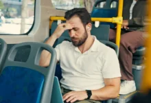 Muž jede v autobusu a drží se za hlavu