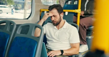 Muž jede v autobusu a drží se za hlavu