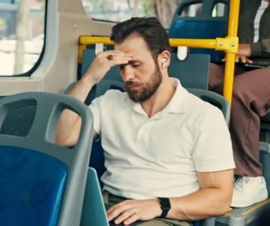 Muž jede v autobusu a drží se za hlavu