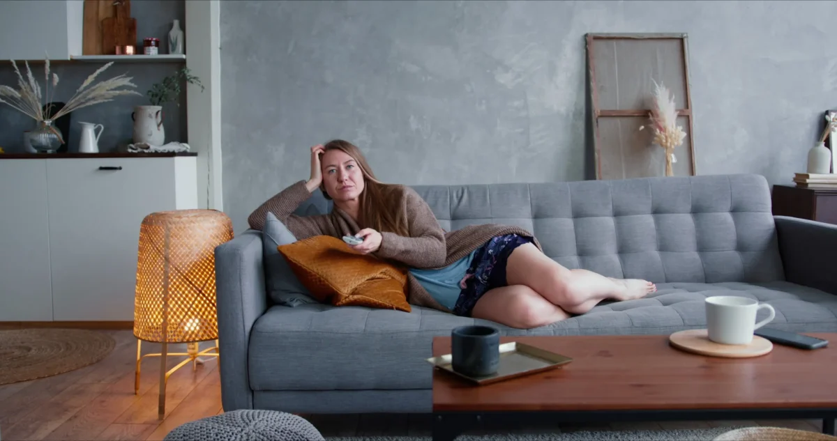 Žena na gauči sledující televizi.