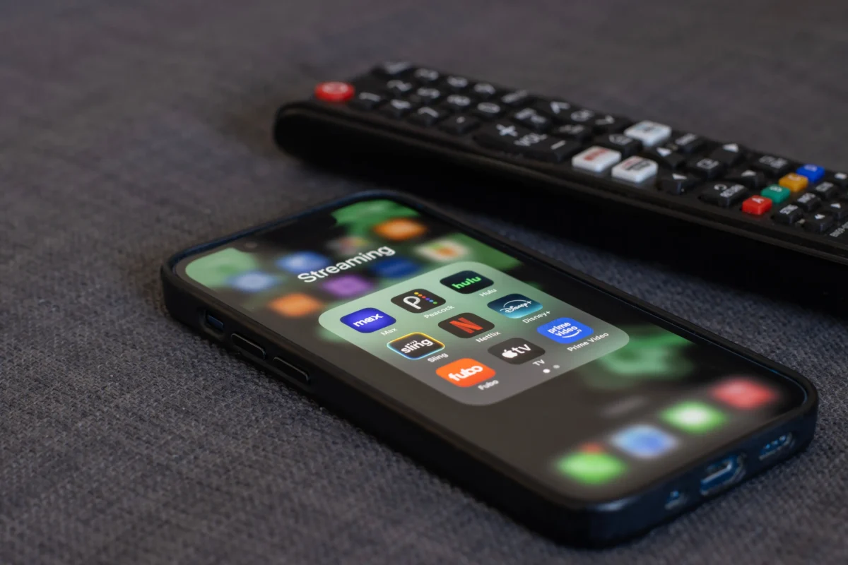 Vedle ovladače leží telefon. 