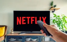 Logo Netflixu na televizi a muž s ovladačem v ruce
