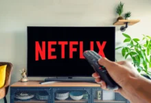 Logo Netflixu na televizi a muž s ovladačem v ruce