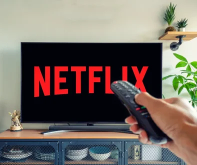 Logo Netflixu na televizi a muž s ovladačem v ruce