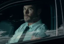 Chris Hemsworth sedí v autě.