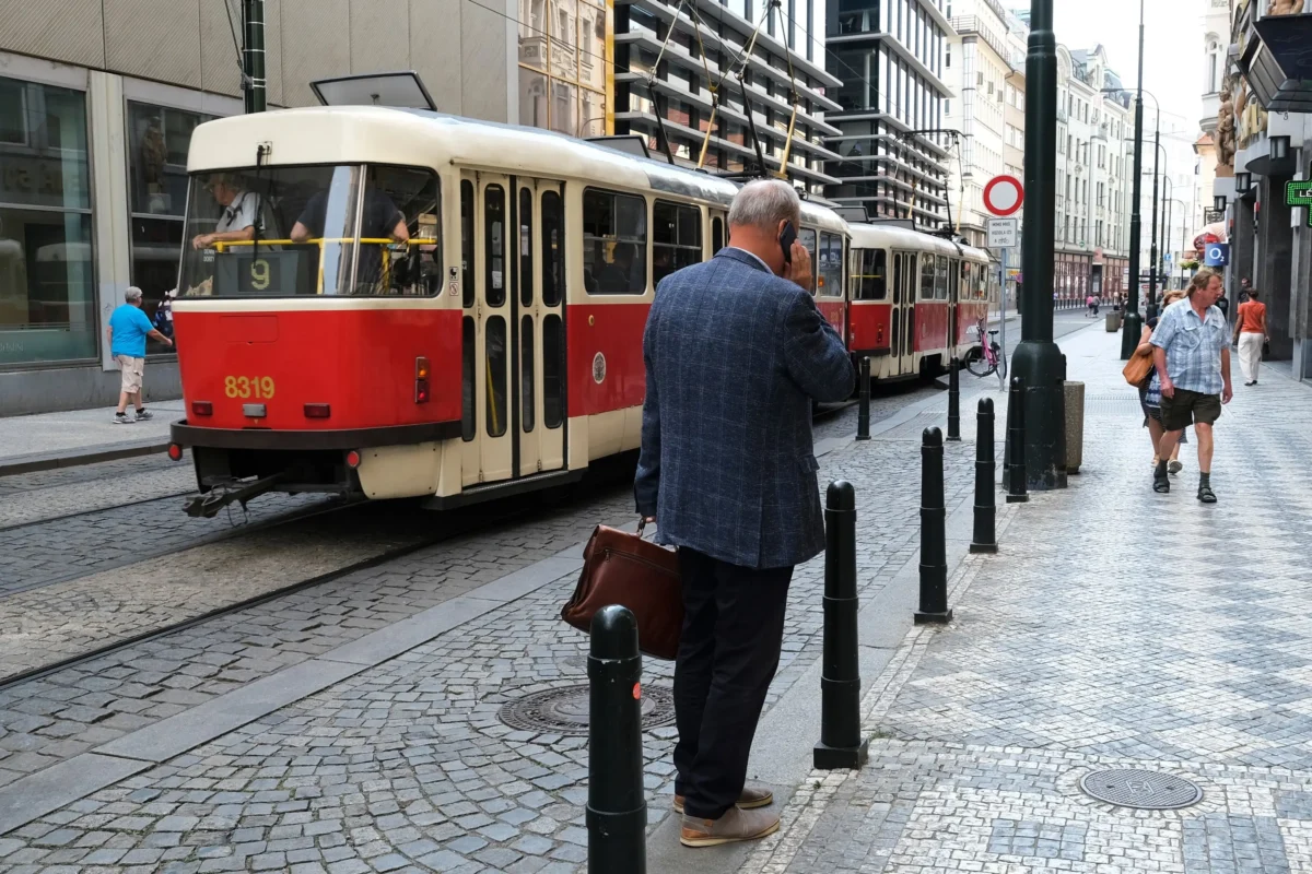 Muž stojí v Praze u tramvaje. 