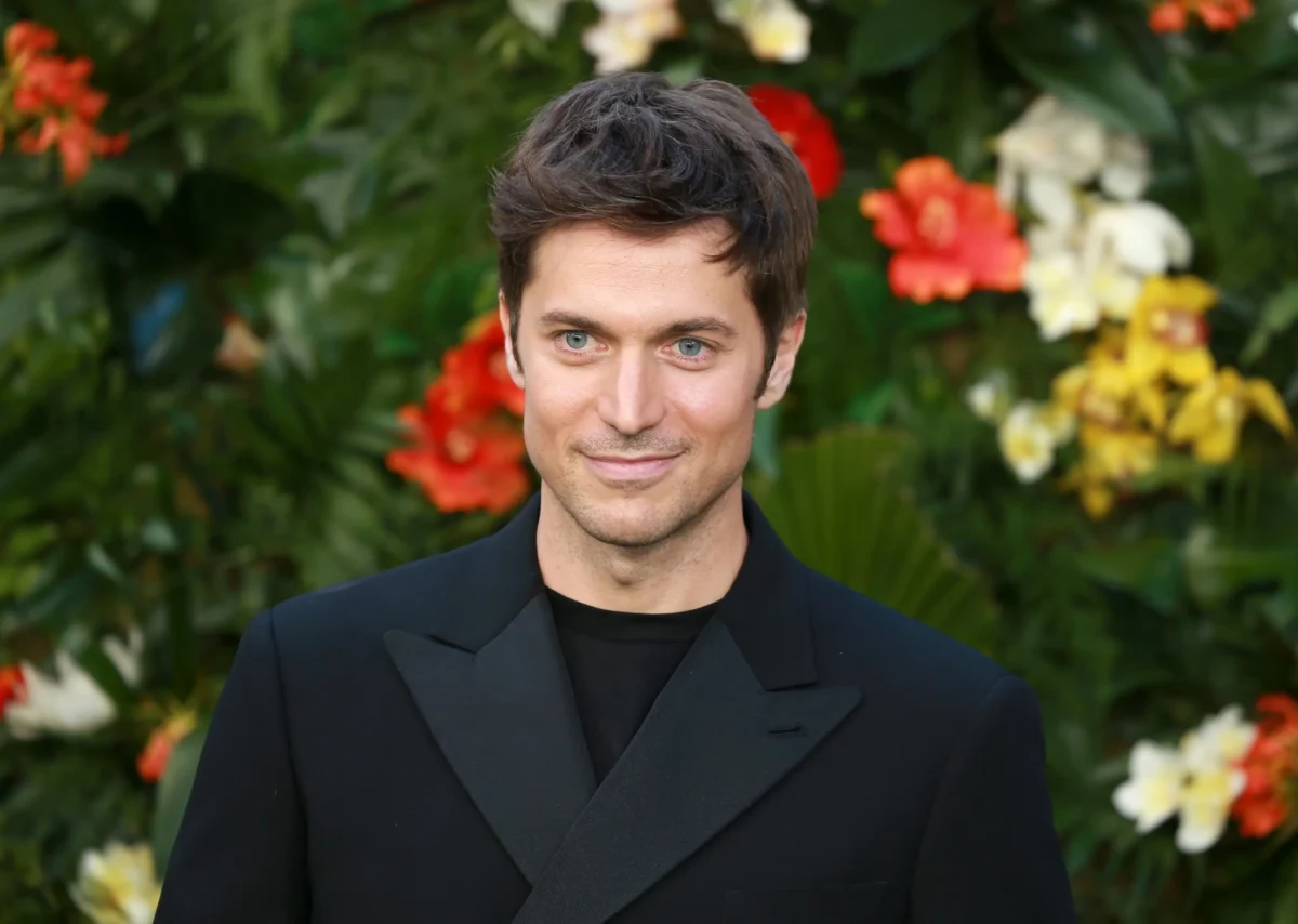 Lucas Bravo se usmívá.