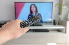 Člověk drží před obrazovkou ovladač.