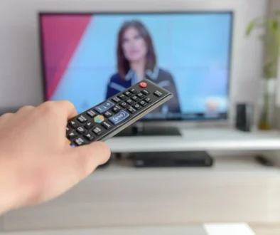 Člověk drží před obrazovkou ovladač.