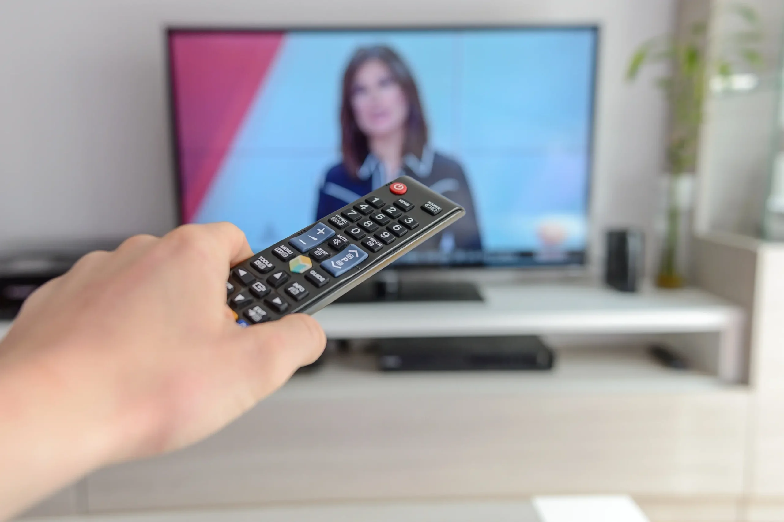 Člověk drží před obrazovkou ovladač.