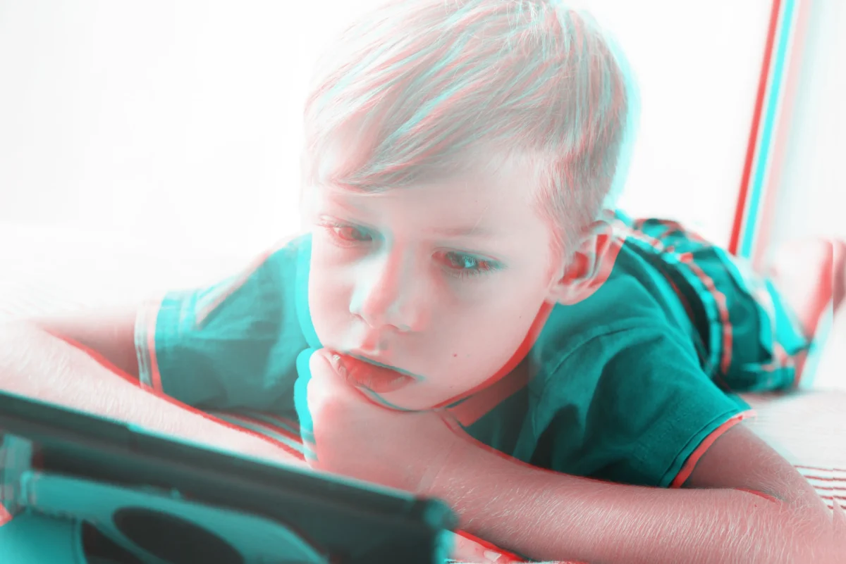 Chlapeček se dívá do telefonu. 