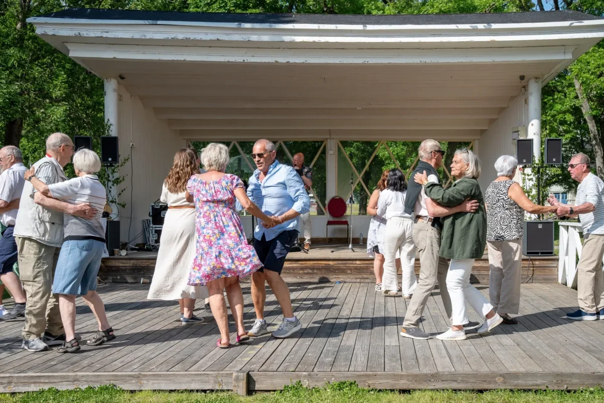 Senioři venku tančí.