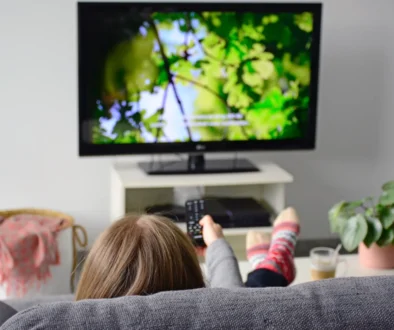 Žena sedí na gauči a sleduje TV.