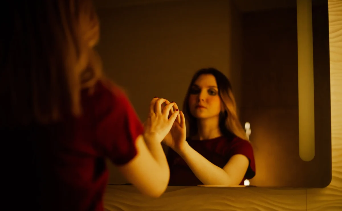 Žena se na sebe dívá do zrcadla. 