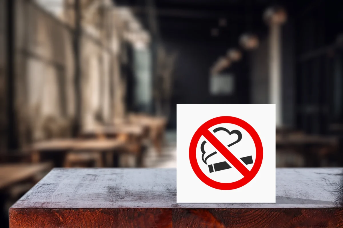 Na stole leží cedulka se zákazem kouření. 